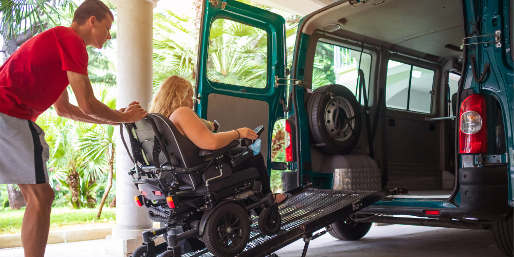 Personne en situation d'handicap entrain de monter sur une rampe dans un véhicule avec un aidant
